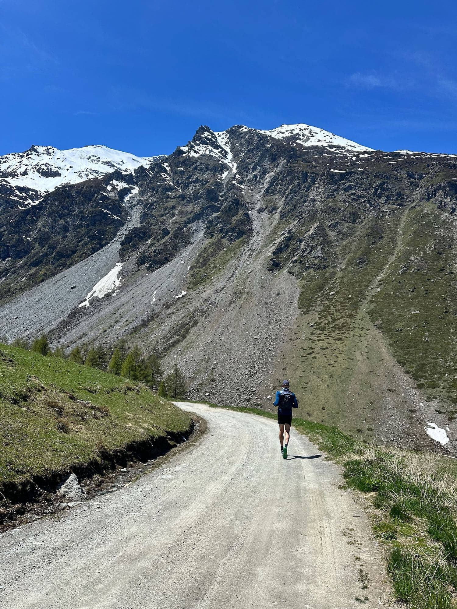 Trail runner su una strada sterrata verso montagne innevate