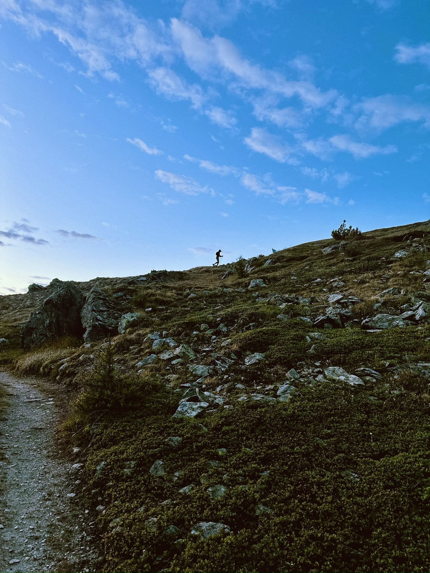 Trail runner su un sentiero di cresta sotto un cielo ampio